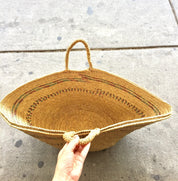 Hand holding a bohemian style straw woven beach bag with intricate design details, an ideal handmade purse or tote for shopping and a unique boho gift idea for her.