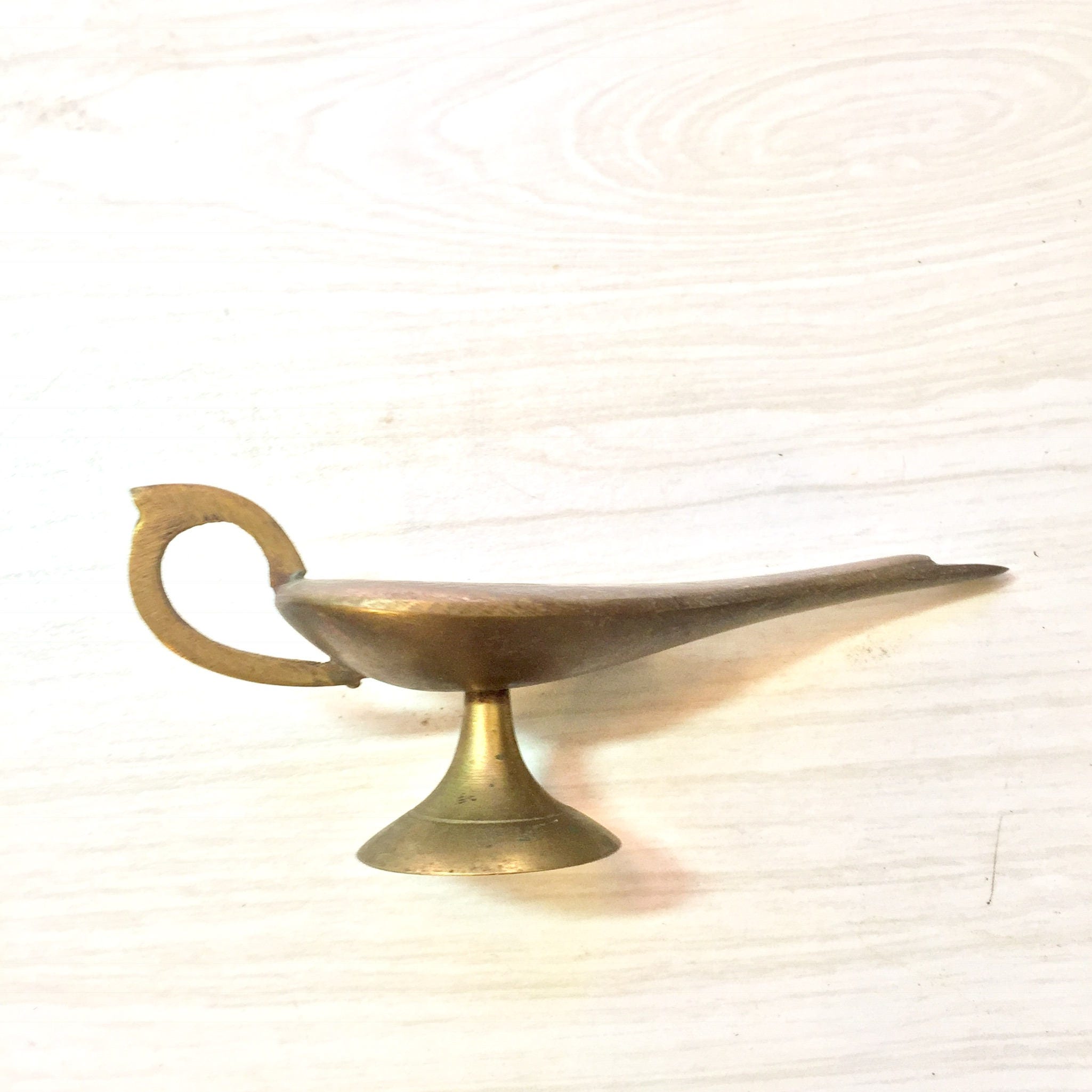 Vintage brass genie lamp incense burner with etched design on white background
