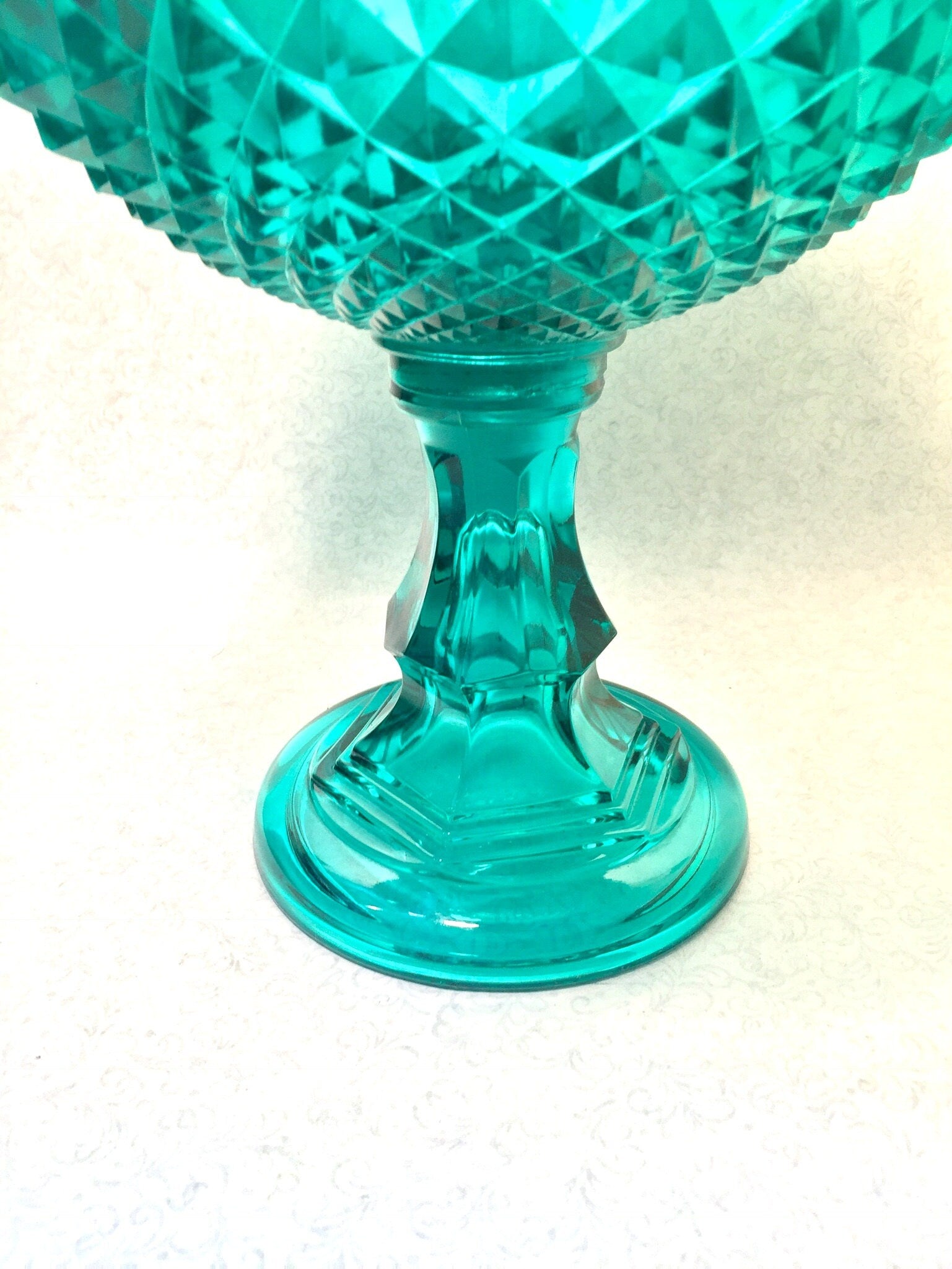 Vintage aqua green cut glass lidded pedestal compote bowl with sawtooth pattern on a white background