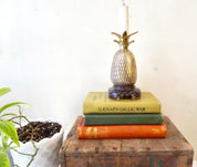 Brass pineapple lamp on vintage books, boho home decor accent lighting