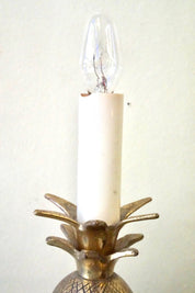 Vintage brass pineapple-shaped table lamp with illuminated candle-like bulb, providing bohemian accent lighting and decor for the home.