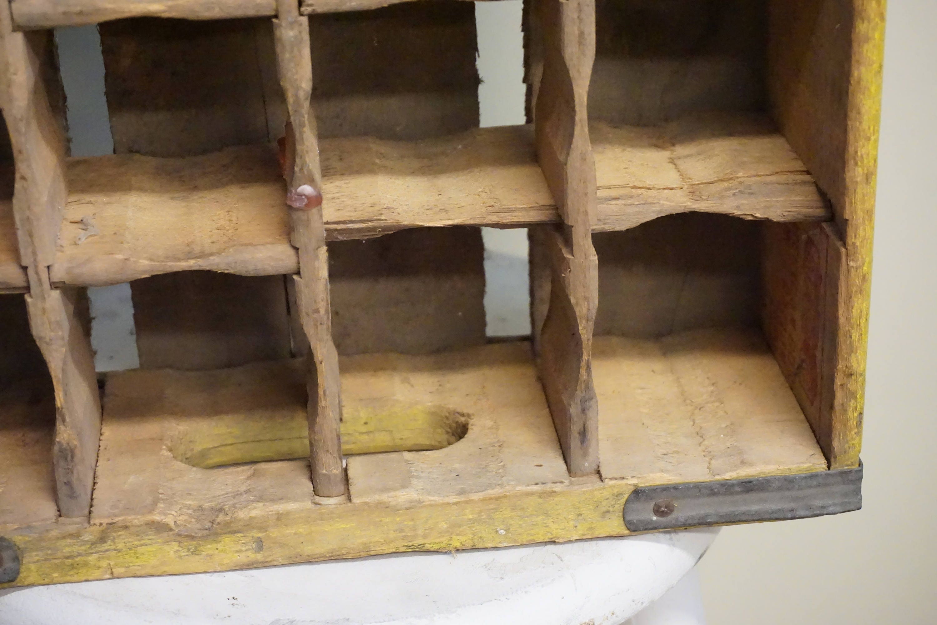 Vintage wooden Coca-Cola bottle crate with multiple compartments and worn yellow paint