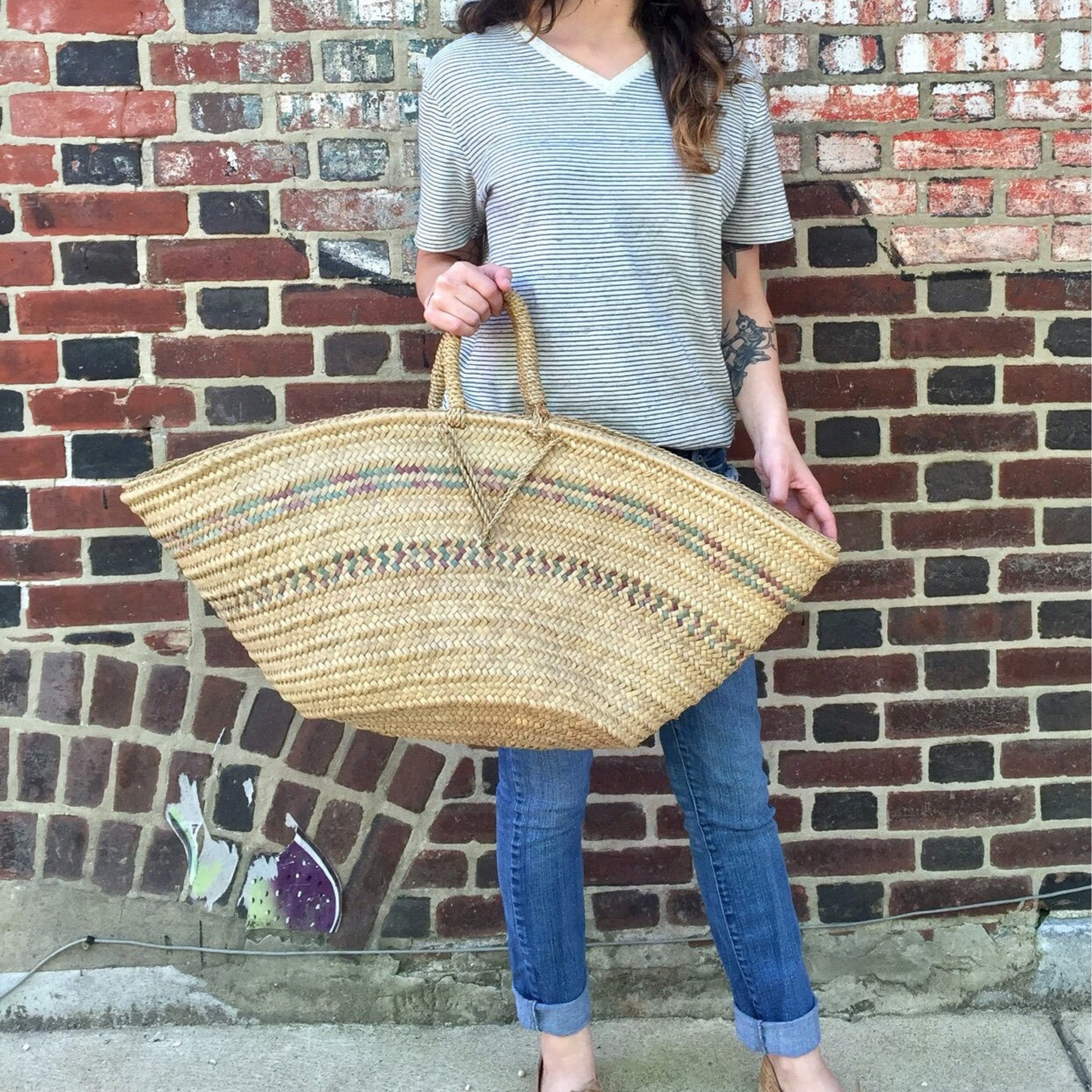 Woman holding a large bohemian-style woven beach tote bag, featuring a straw design and handmade craftsmanship, perfect as a stylish boho accessory or a unique gift idea for her.