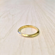 18K yellow gold thin stacking ring on light wooden surface