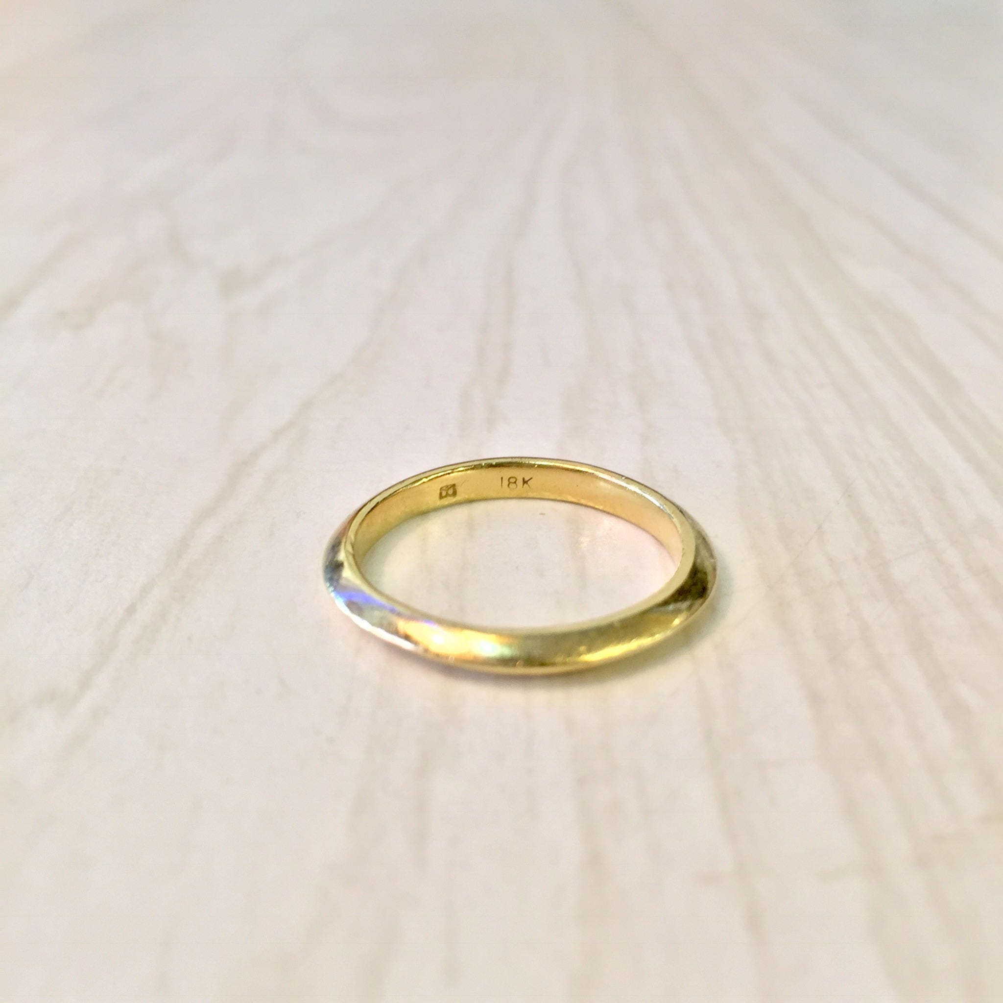 18K yellow gold thin stacking ring on light wooden surface