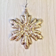 Vintage Gorham sterling silver snowflake Christmas ornament hanging against a light wood background