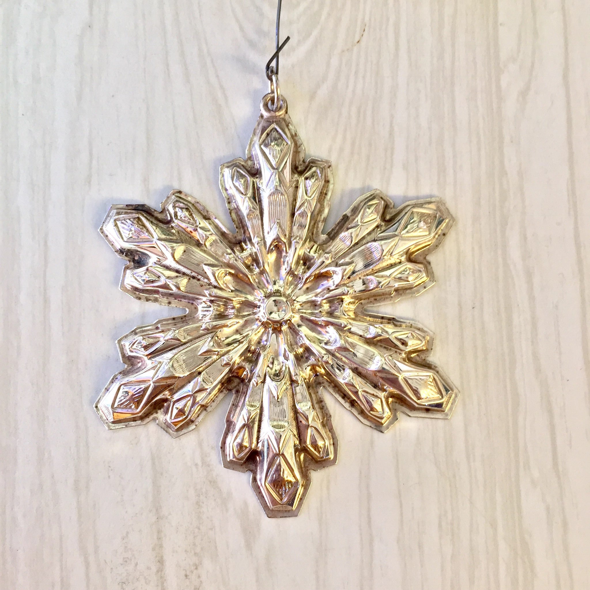 Vintage Gorham sterling silver snowflake Christmas ornament hanging against a light wood background