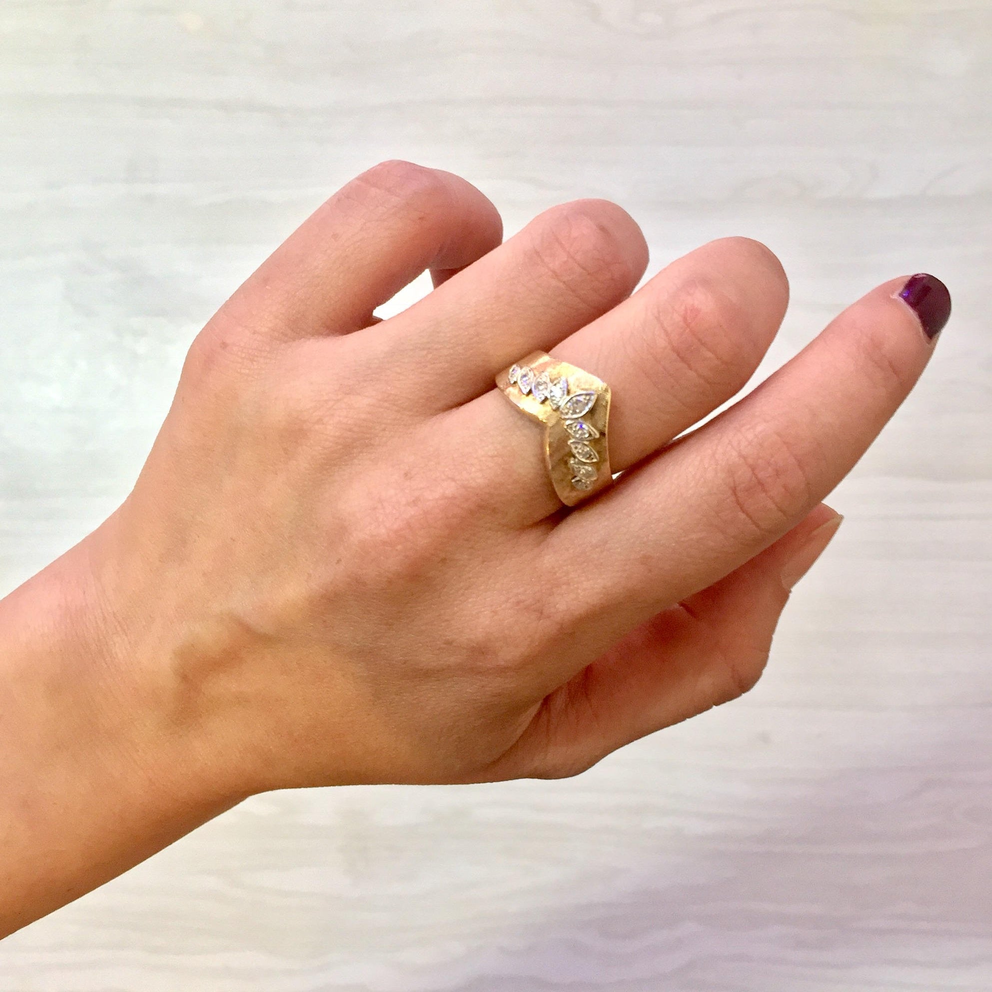 14K yellow gold chevron V-shaped stackable diamond ring on a hand against a white background