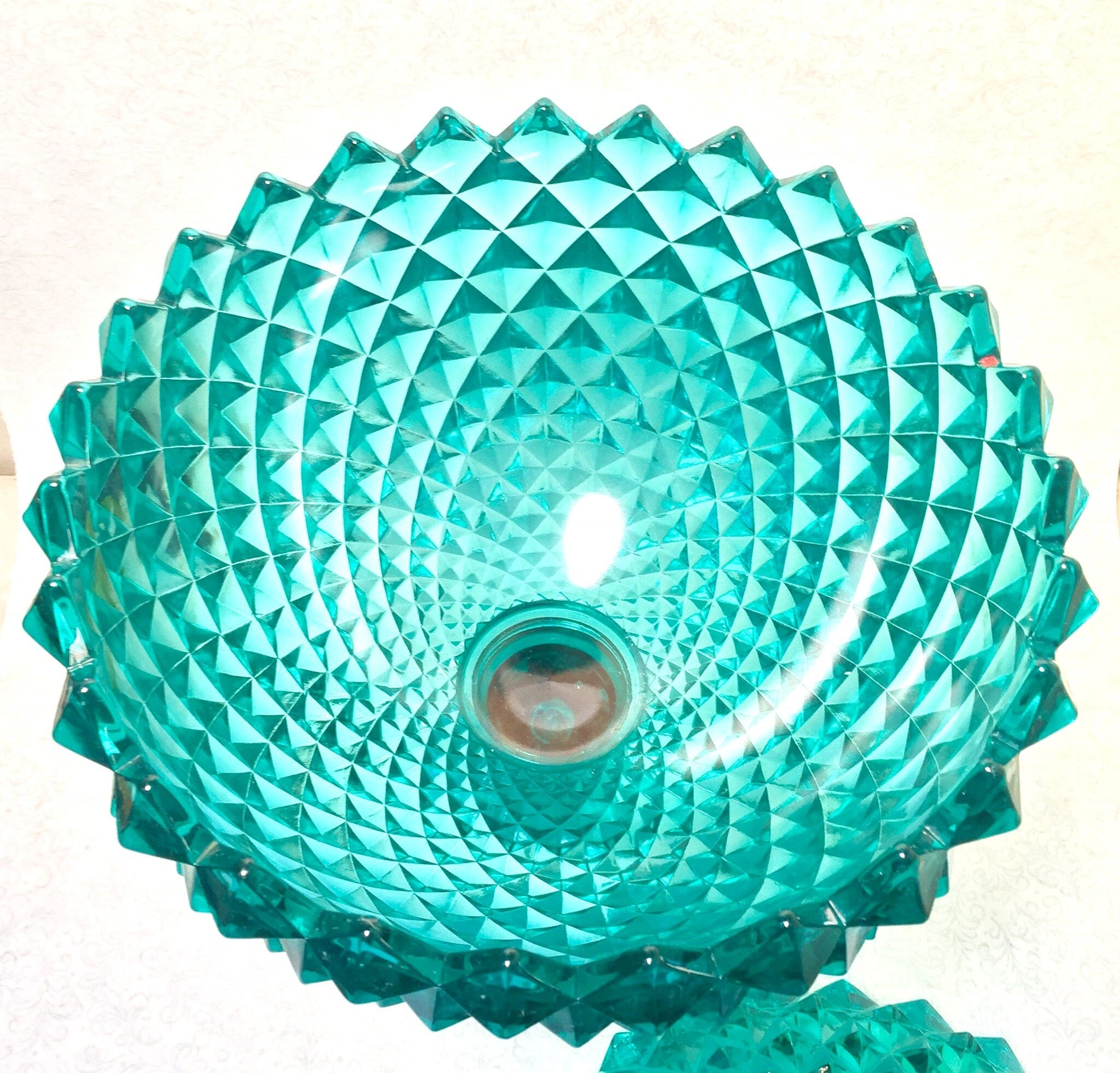 Large aqua green sawtooth patterned depression glass lidded pedestal compote bowl, made by Indiana Glass. The intricate sawtooth design creates a vibrant textured effect on the bowl's surface. Covered glass compote dish serves as an elegant home decor piece or special occasion gift.