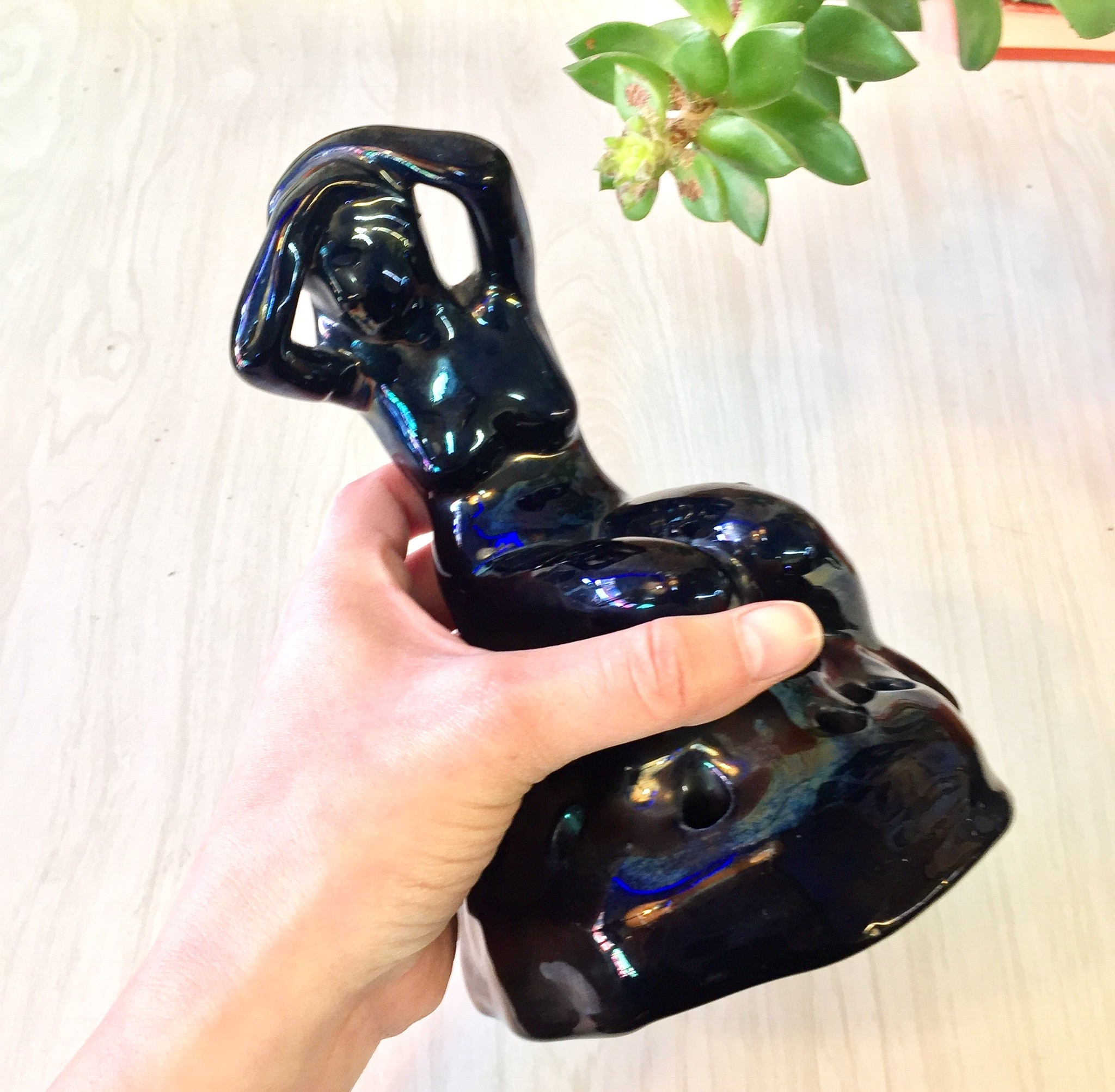 Black iridescent ceramic naked lady figurine flower frog, Art Deco style sculpture for floral arrangements, held in hand with succulent plant in background