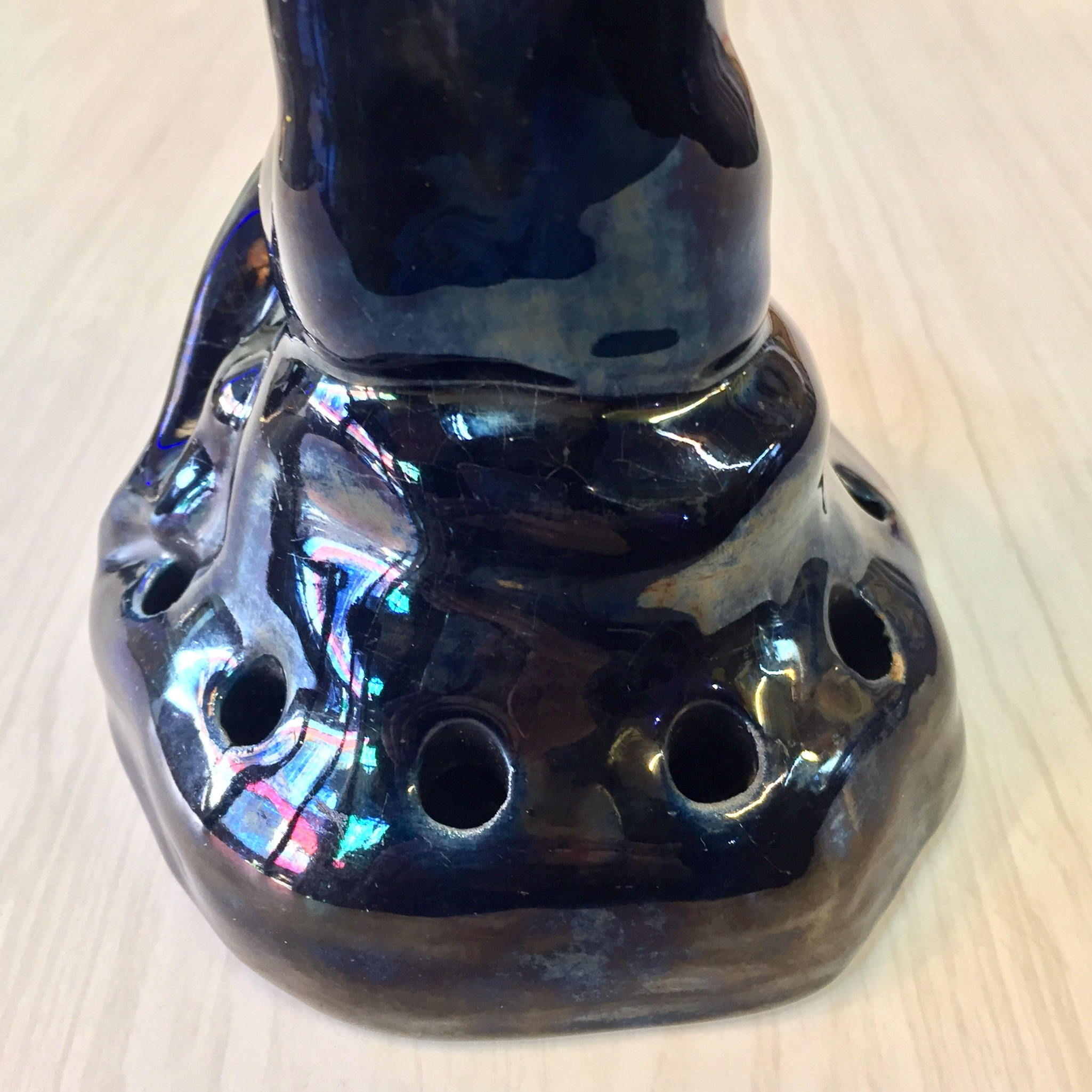 Glazed ceramic naked lady flower frog in black with iridescent accents, featuring holes for floral arrangements in an Art Deco style design.