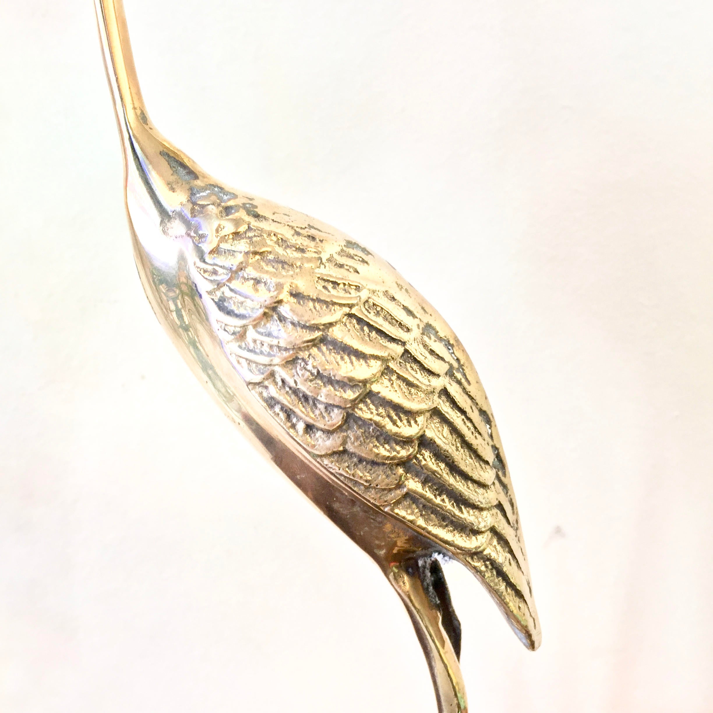 Vintage brass crane statue with detailed feather textures, curved neck, and elongated beak, in a midcentury modern style for home decor or as a unique gift.