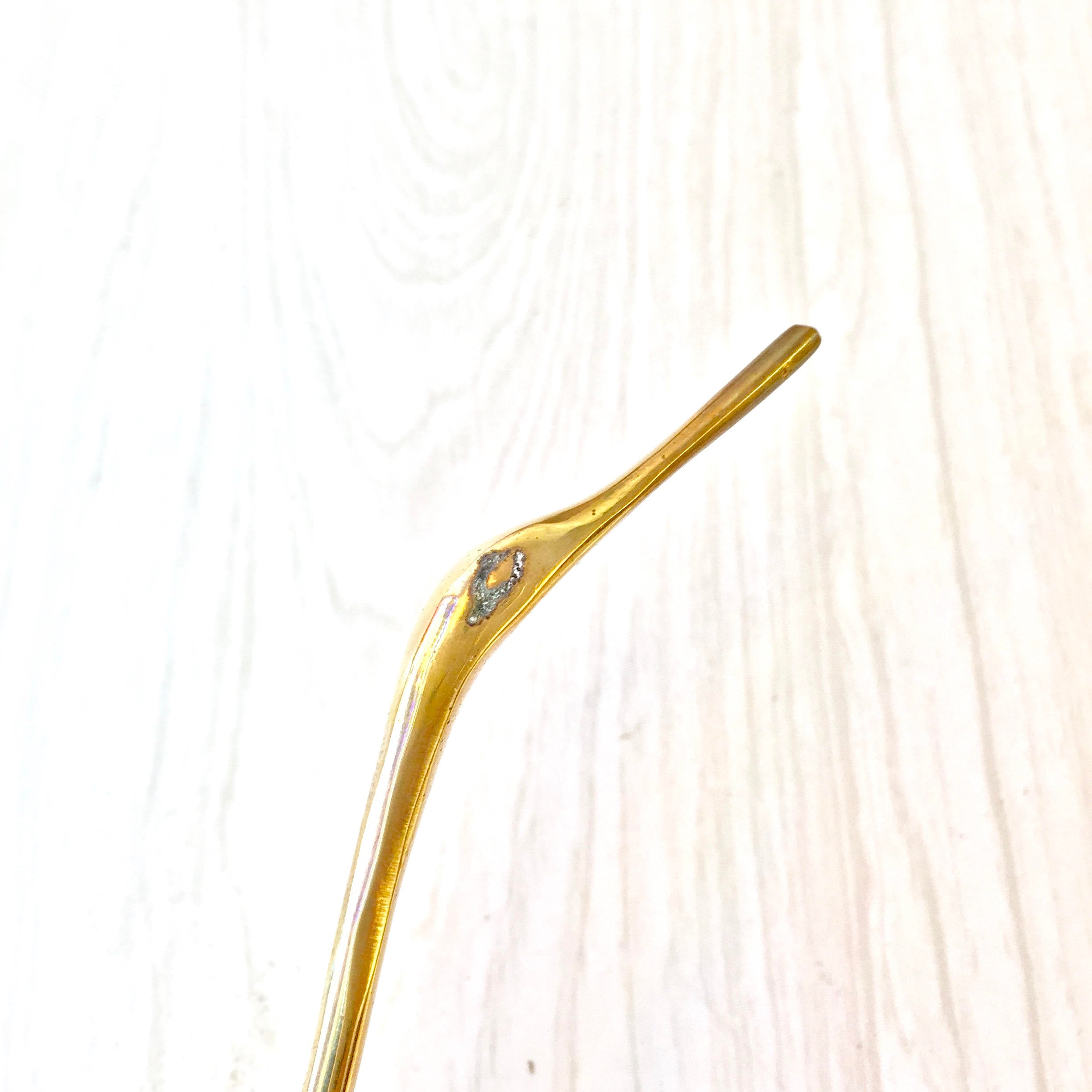 Vintage brass crane statue on a light wood background, midcentury modern style brass bird figurine for home decor