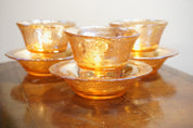 Set of three vintage orange carnival glass dessert dishes with an iridescent shine, stacked on a wooden surface.