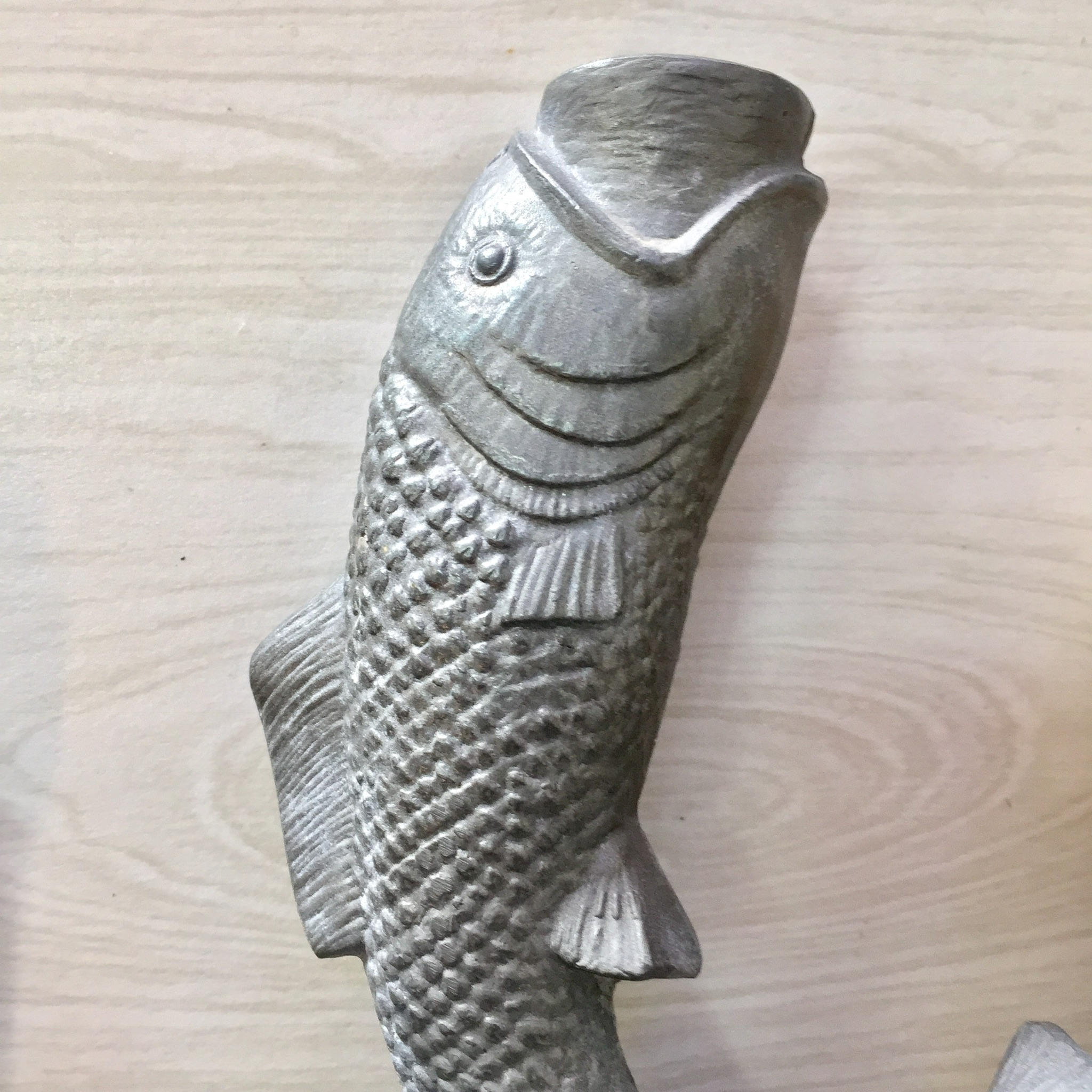 Vintage pewter fish-shaped candlestick holder with textured scales and fins, sitting upright on a wooden surface.