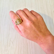 Close-up of a hand wearing a vintage 10 karat gold ring featuring a lion's head design accented with small diamonds, resting on a white wooden surface.