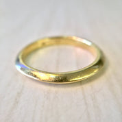 18K yellow gold thin, simple stacking ring or wedding band with a sleek, polished finish, shown close-up on a light background.