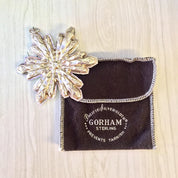 Vintage Gorham sterling silver snowflake Christmas ornament in original pouch on wooden surface
