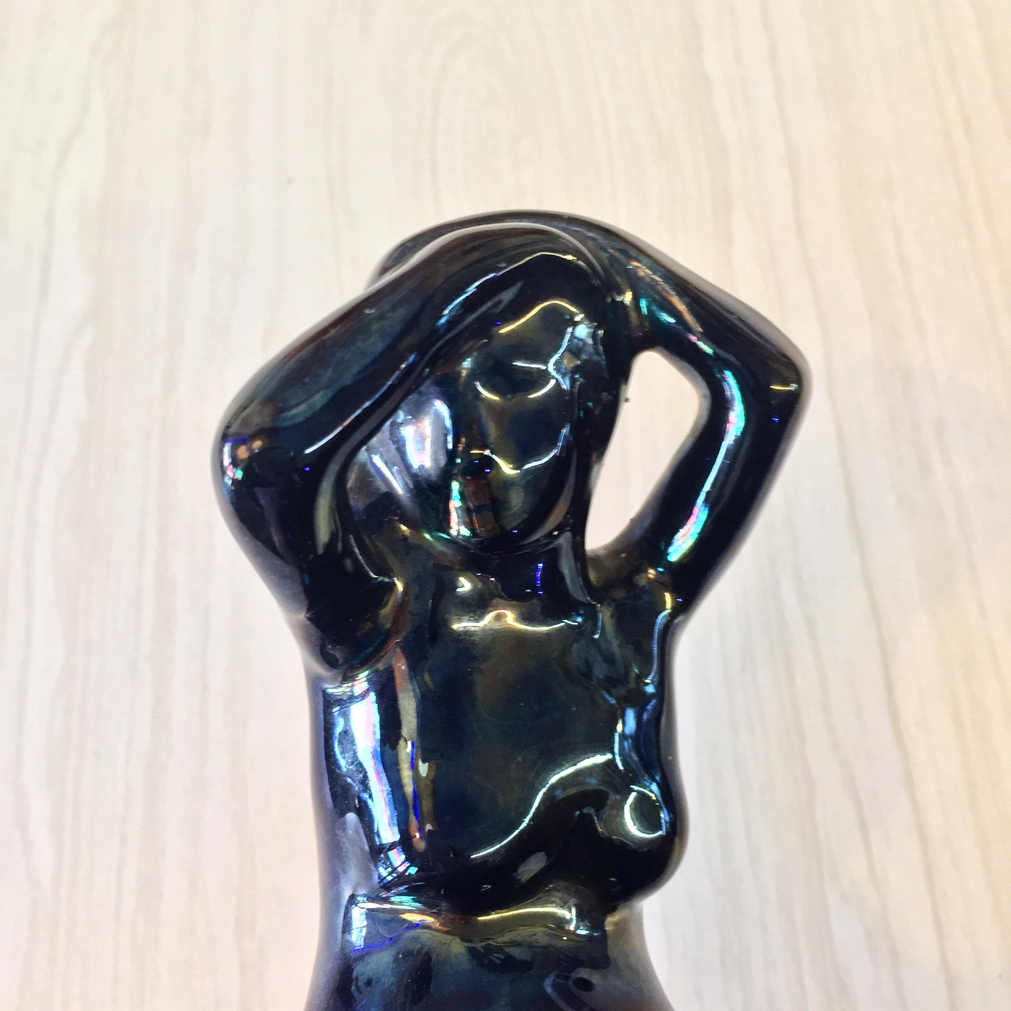 Abstract black ceramic flower frog sculpture depicting a stylized female figure in an Art Deco style, with an iridescent glaze creating colorful reflections on the shiny surface.