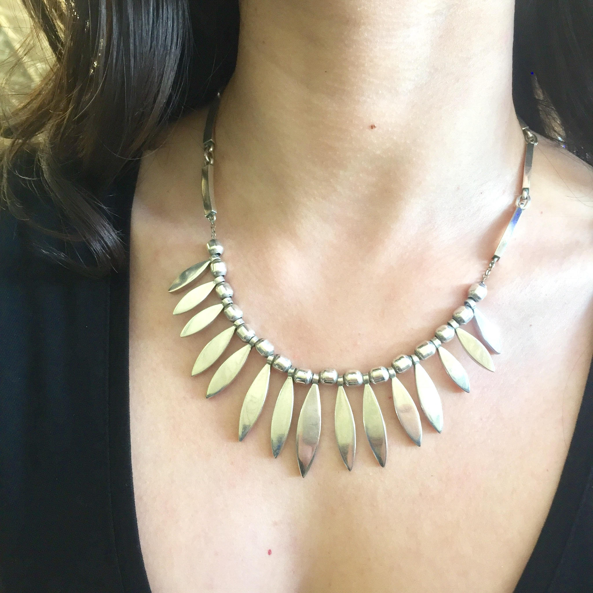 Vintage sterling silver bib necklace with pointed oval pendants worn on a woman's neck and chest.