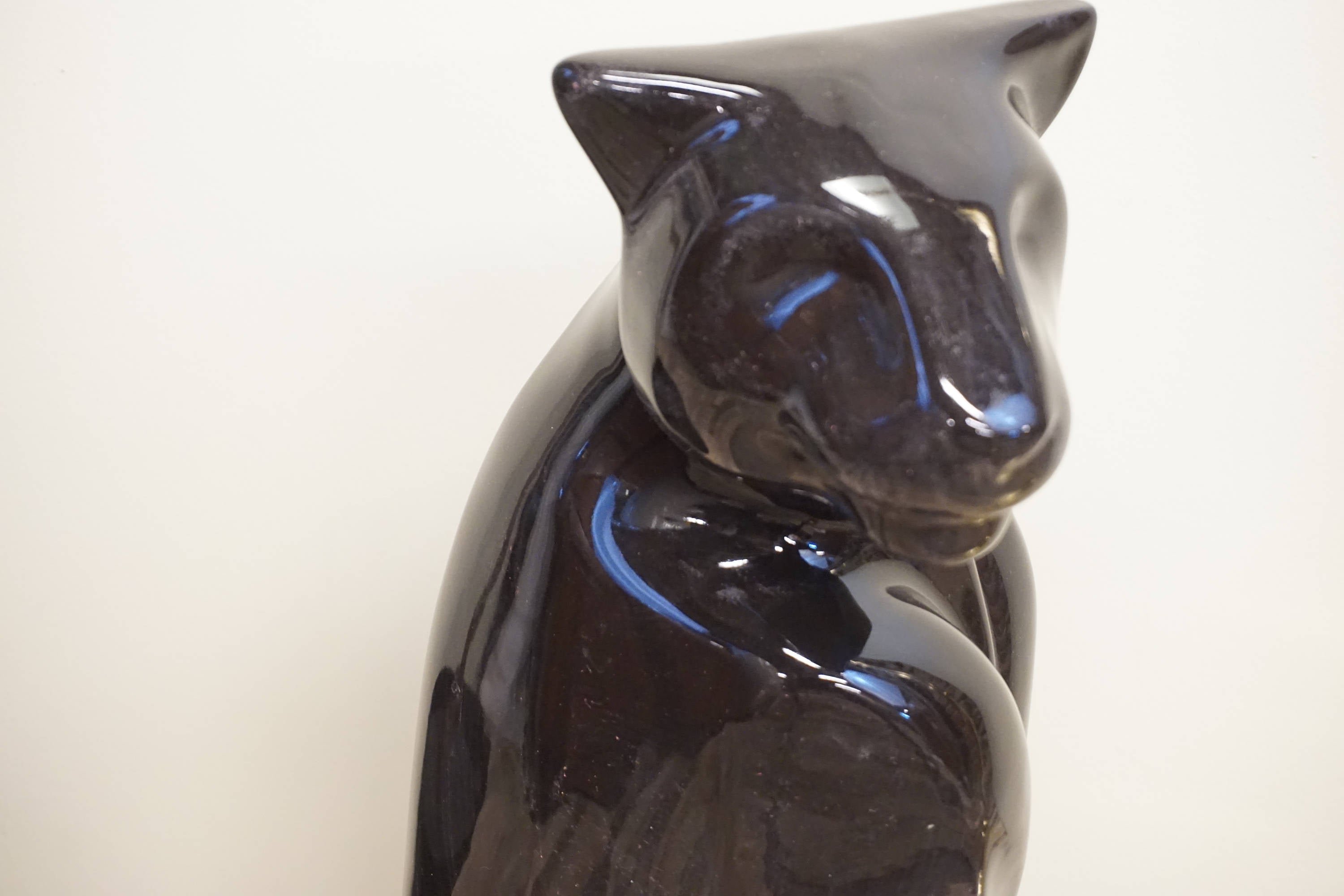 Black ceramic Royal Haeger panther statue from the 1970s with glossy glaze finish, depicting a sitting panther with elegant curved tail and ears, a vintage home decor collectible piece.