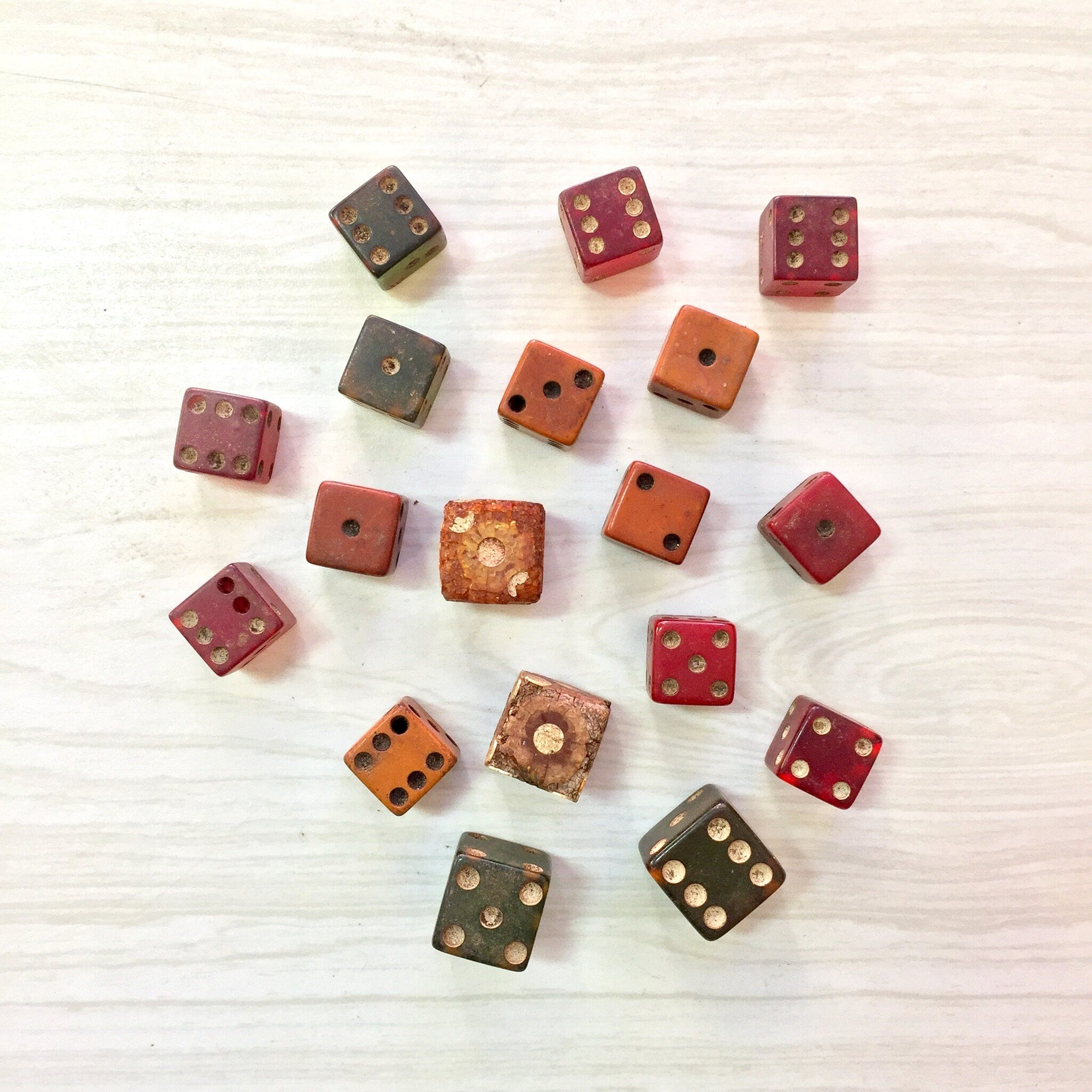 Antique wooden dice in various colors including red, brown, orange, and green, arranged on a light wooden background, lot of 18 vintage gaming dice for arts and crafts.