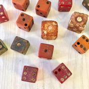 Antique wooden dice in assorted colors and sizes, some with gold painted dots, scattered on a white textured surface, suitable for vintage games or arts and crafts projects.