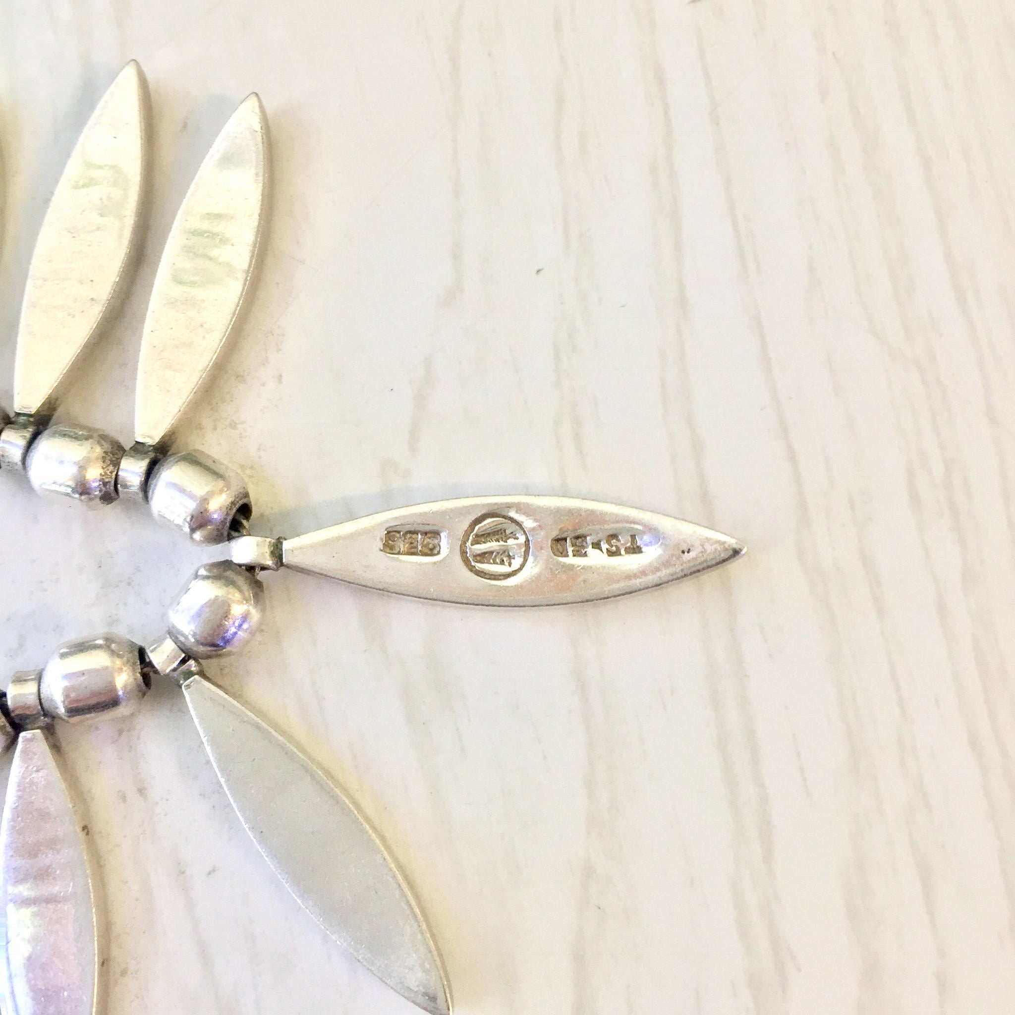 Vintage sterling silver bib necklace with beaded accents on a light wood background
