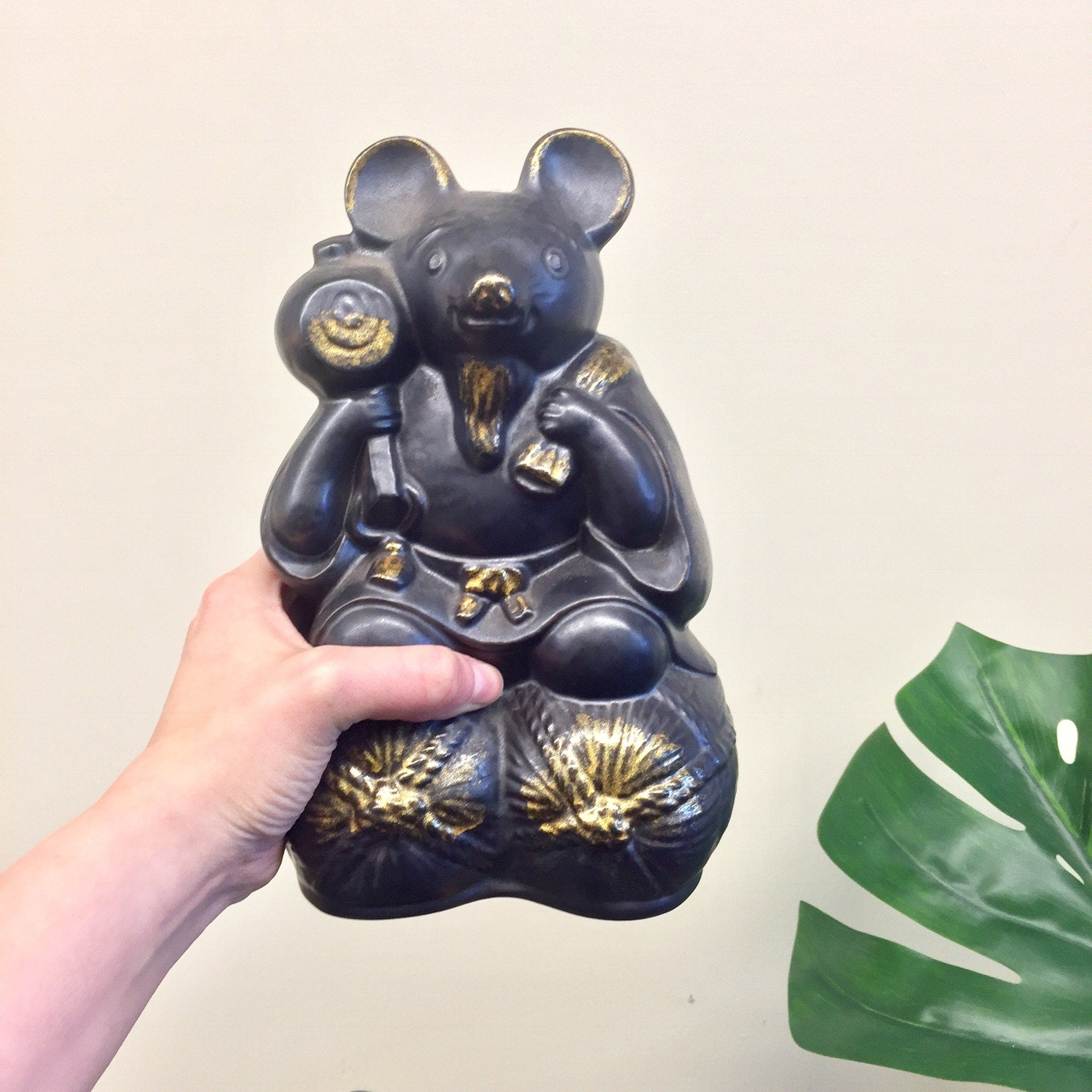 Large vintage black and gold ceramic sake bottle shaped like a rat or mouse holding smaller bottles, with a green plant leaf, unique Asian home decor