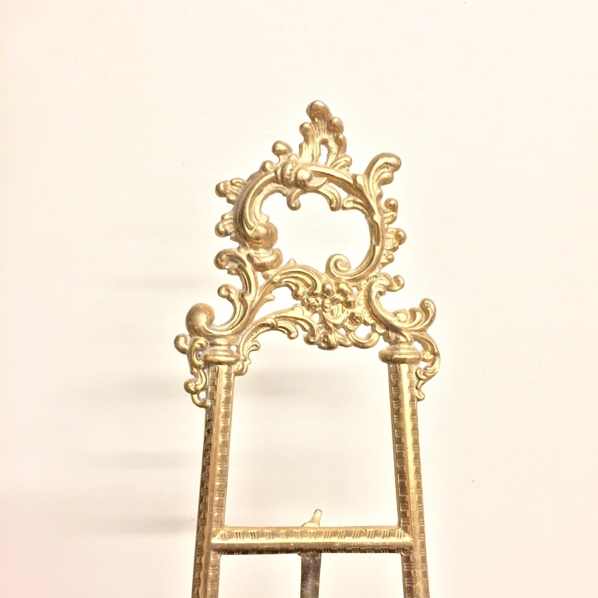 Ornate vintage brass easel with intricate filigree design, ideal for displaying books, cookbooks, or frames in a bohemian chic home decor style.