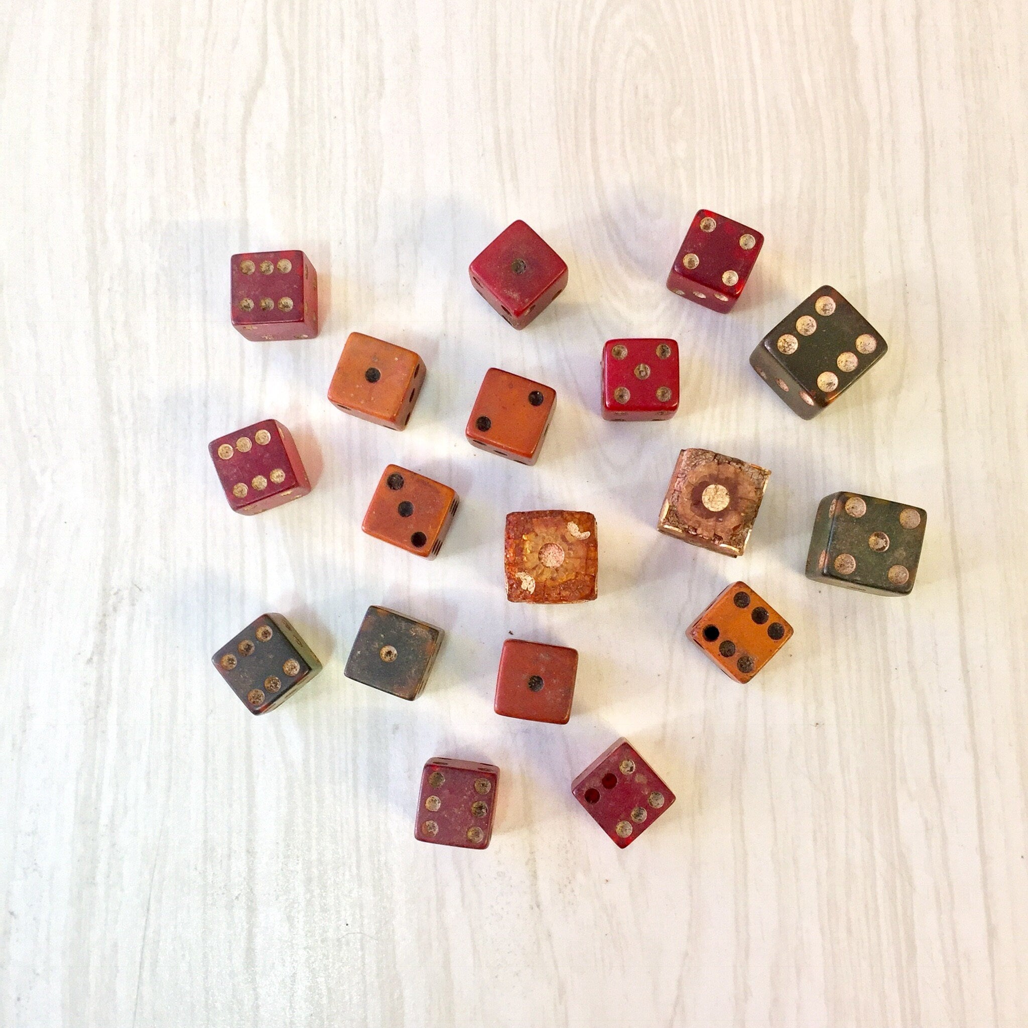 Antique wooden dice in assorted colors and designs scattered on a light wood surface, lot of 18 vintage gaming dice for arts and crafts projects