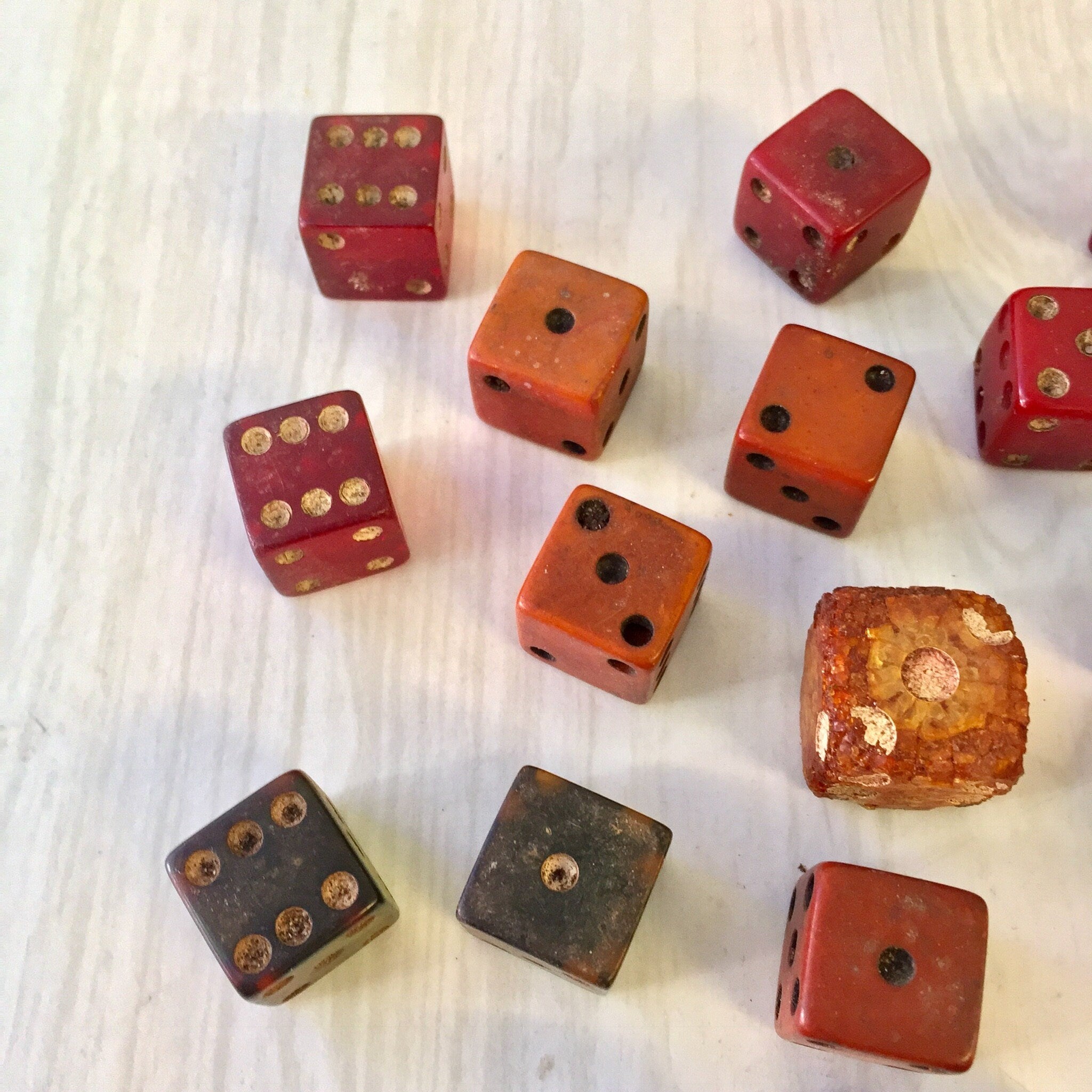 Assortment of antique red and black wooden dice with various dot patterns on a white background, including square and rounded cube shapes in different sizes, totaling 18 vintage game dice pieces.