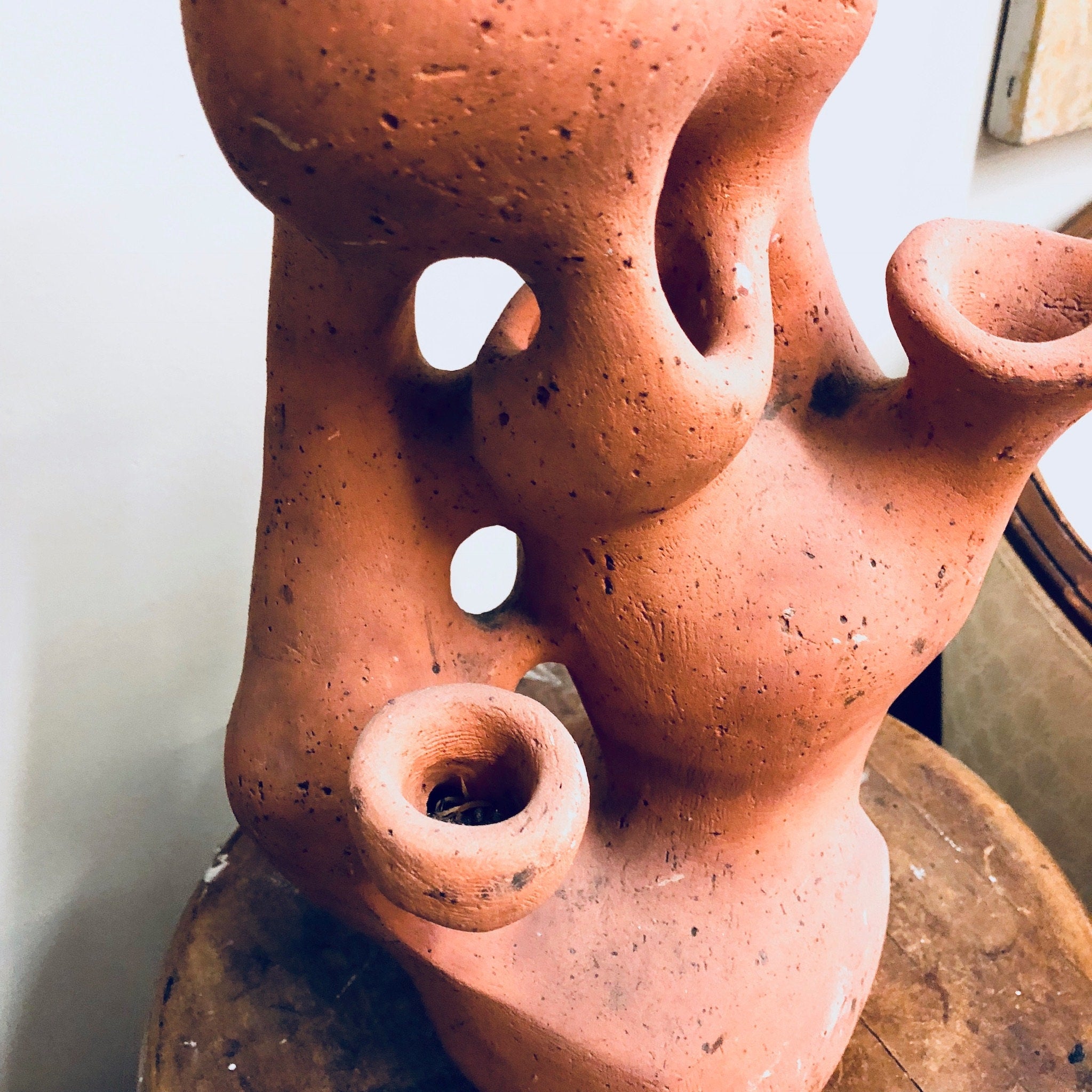 Rustic terracotta strawberry pot with multiple holes for herbs or strawberry plants, handcrafted from natural clay with an organic, sculptural shape and earthy texture.