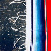 Vintage Mexican blanket with bright stripes of red, blue, green and white on dark background, fringed edges, close-up detail of textured woven fibers and tassels