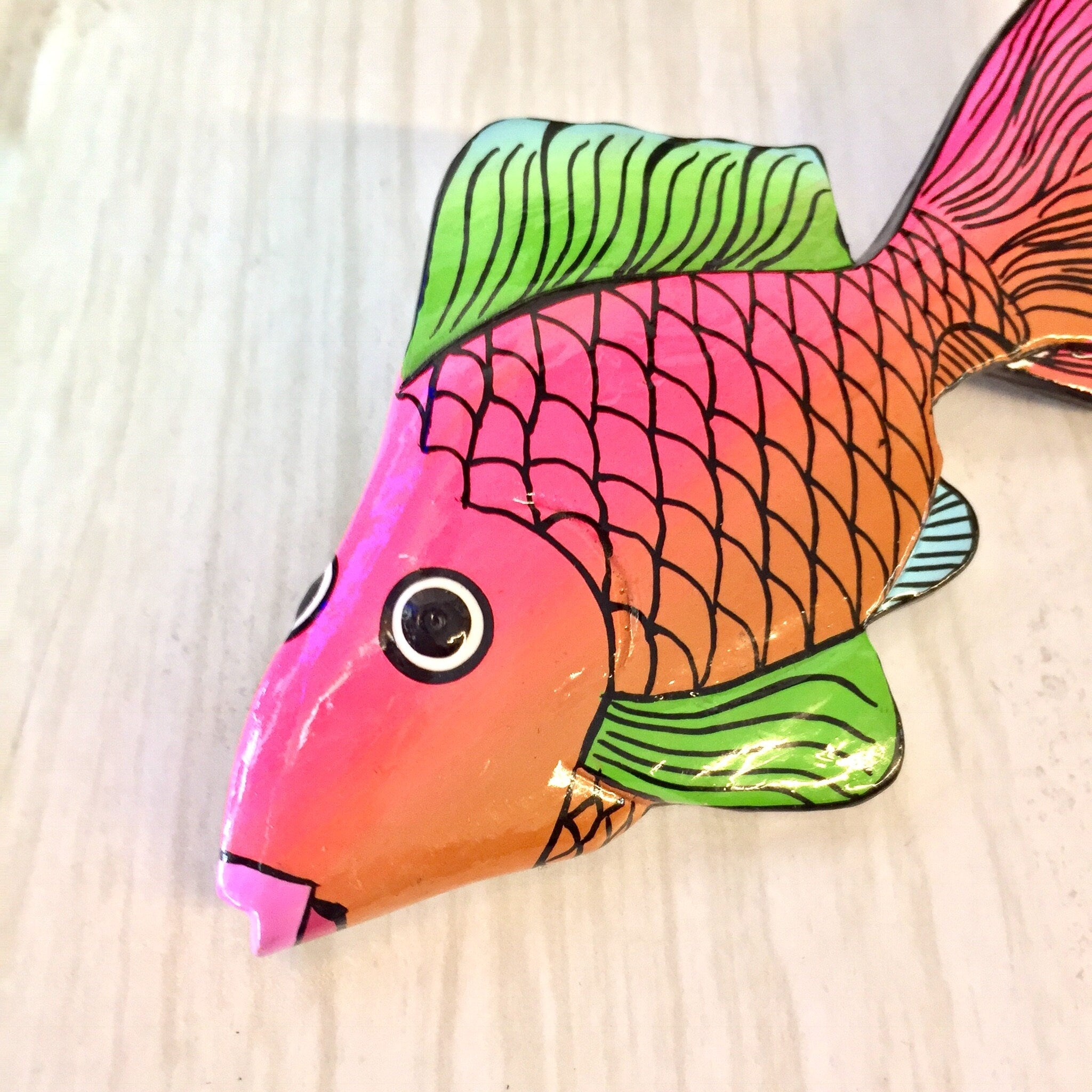 Colorful wooden fish brooch pin featuring pink, orange and green scales in a stylized geometric pattern, vintage jewelry accessory.