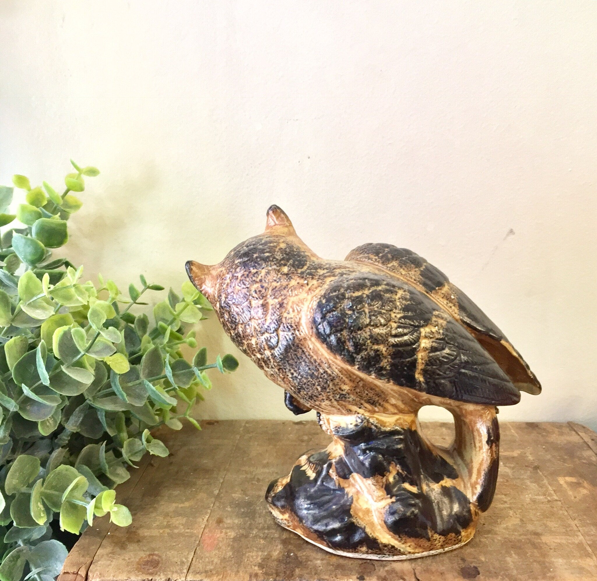 Vintage ceramic owl figurine with brown and black glaze, perched next to green foliage on a wooden surface, perfect for home decor or as a Mother's Day gift.