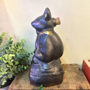Vintage blue and gold glazed ceramic sake bottle in the shape of a sitting rat or mouse figurine, displayed on a wooden surface with greenery in the background.