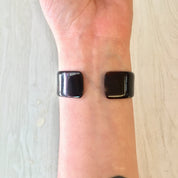 Vintage brown tortoise shell plastic cuff bracelet on person's wrist, costume jewelry from retro era, small size bracelet.