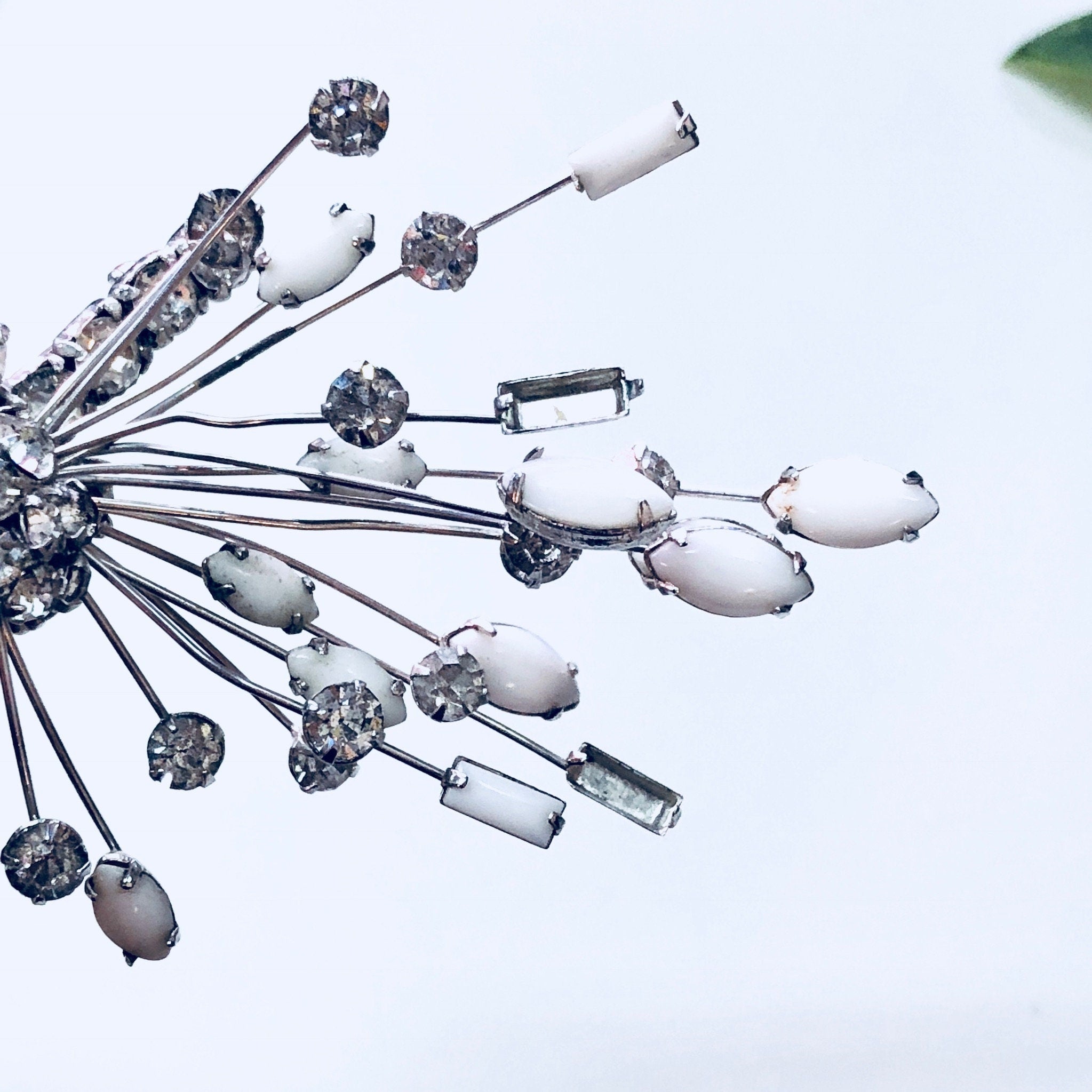 Silver rhinestone floral spray brooch and clip-on earrings set from Marvella featuring white stones in an art deco style design.