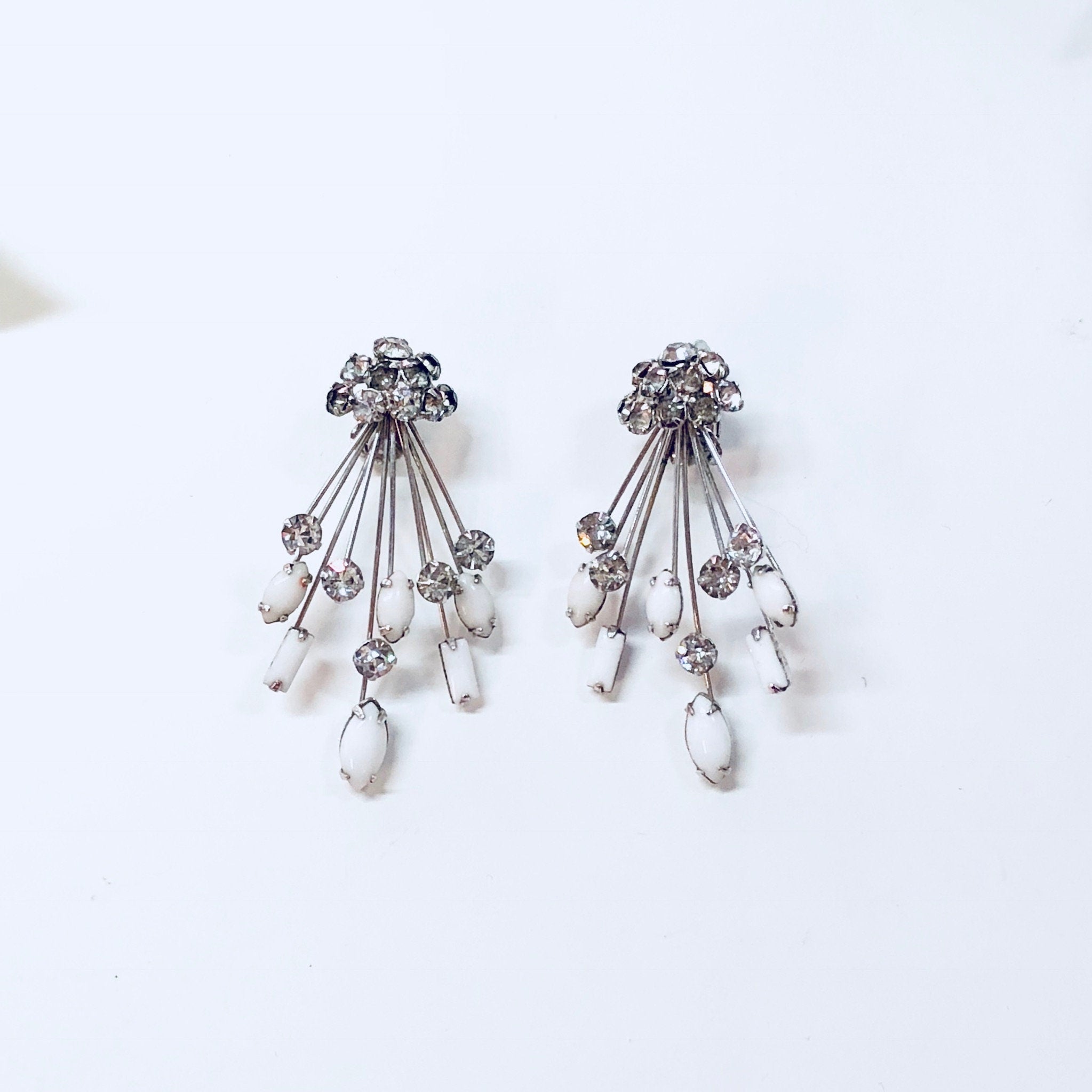 Marvella silver tone clip-on earrings with clear rhinestones and matching Art Deco style brooch pin featuring white stones and dangling teardrops.