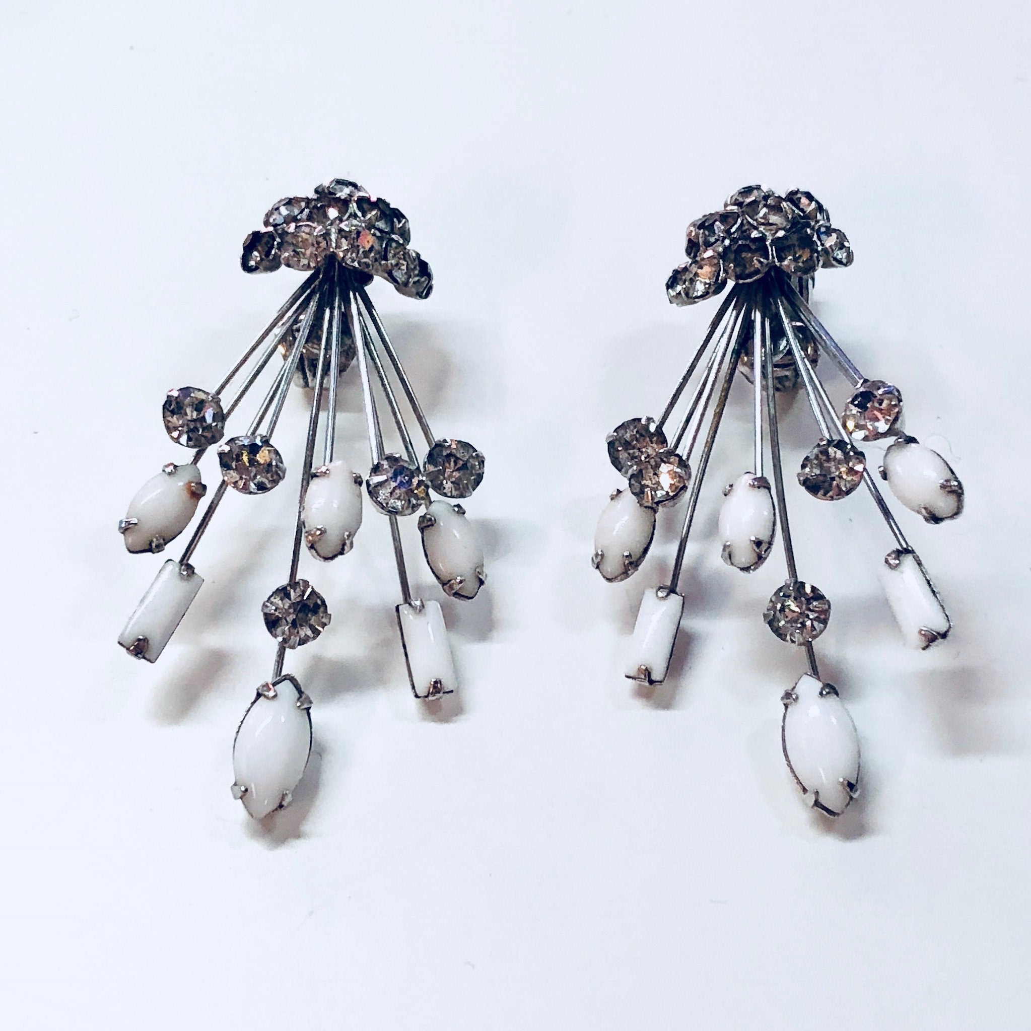 Pair of vintage Marvella silver tone fan-shaped brooches or clip-on earrings with dangling rhinestones and white stones in an Art Deco style design.