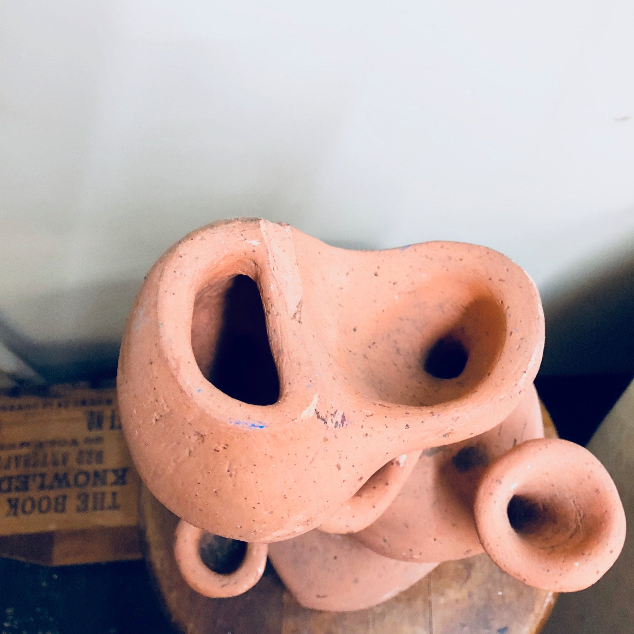 Handmade terracotta strawberry planter pot with multiple openings for herb or strawberry plants, unglazed natural clay finish, photographed on a blurred outdoor background