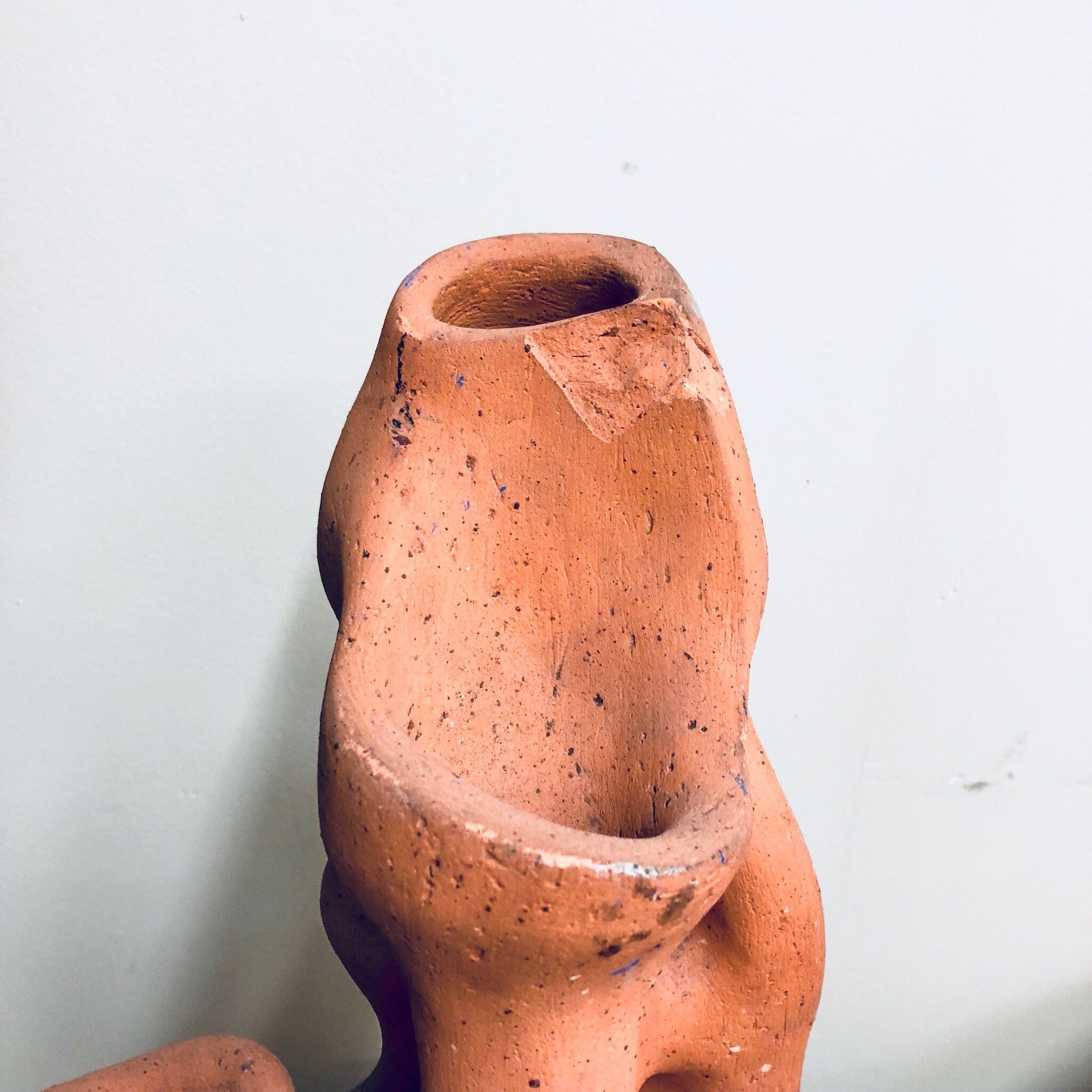Terracotta strawberry planter pot with unique organic textured surface and opening at the top, crafted from natural clay for herbs or strawberry plants in the garden.