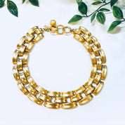 Vintage gold-toned chain link choker necklace by Anne Klein with toggle clasp, displayed on white background with greenery accents.
