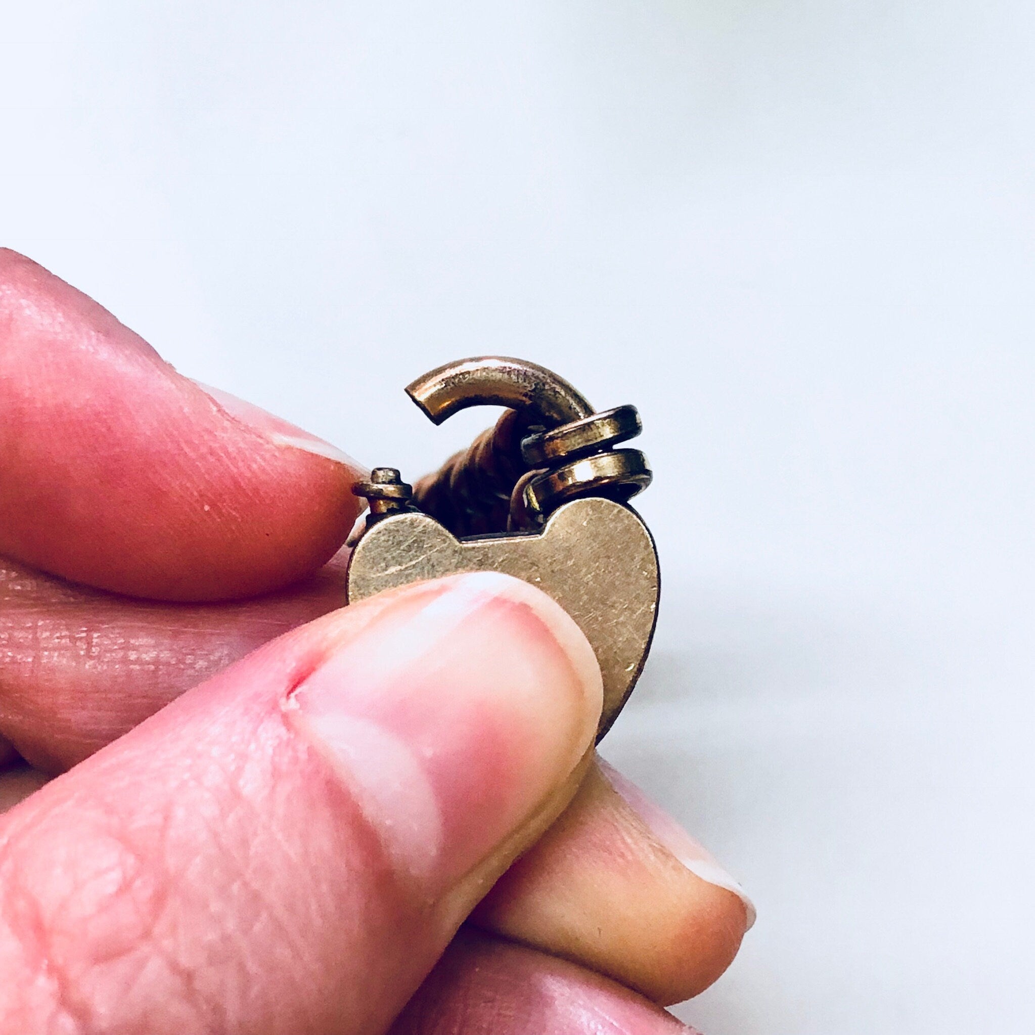 Vintage gold-toned heart locket bracelet with thick chain held in fingers