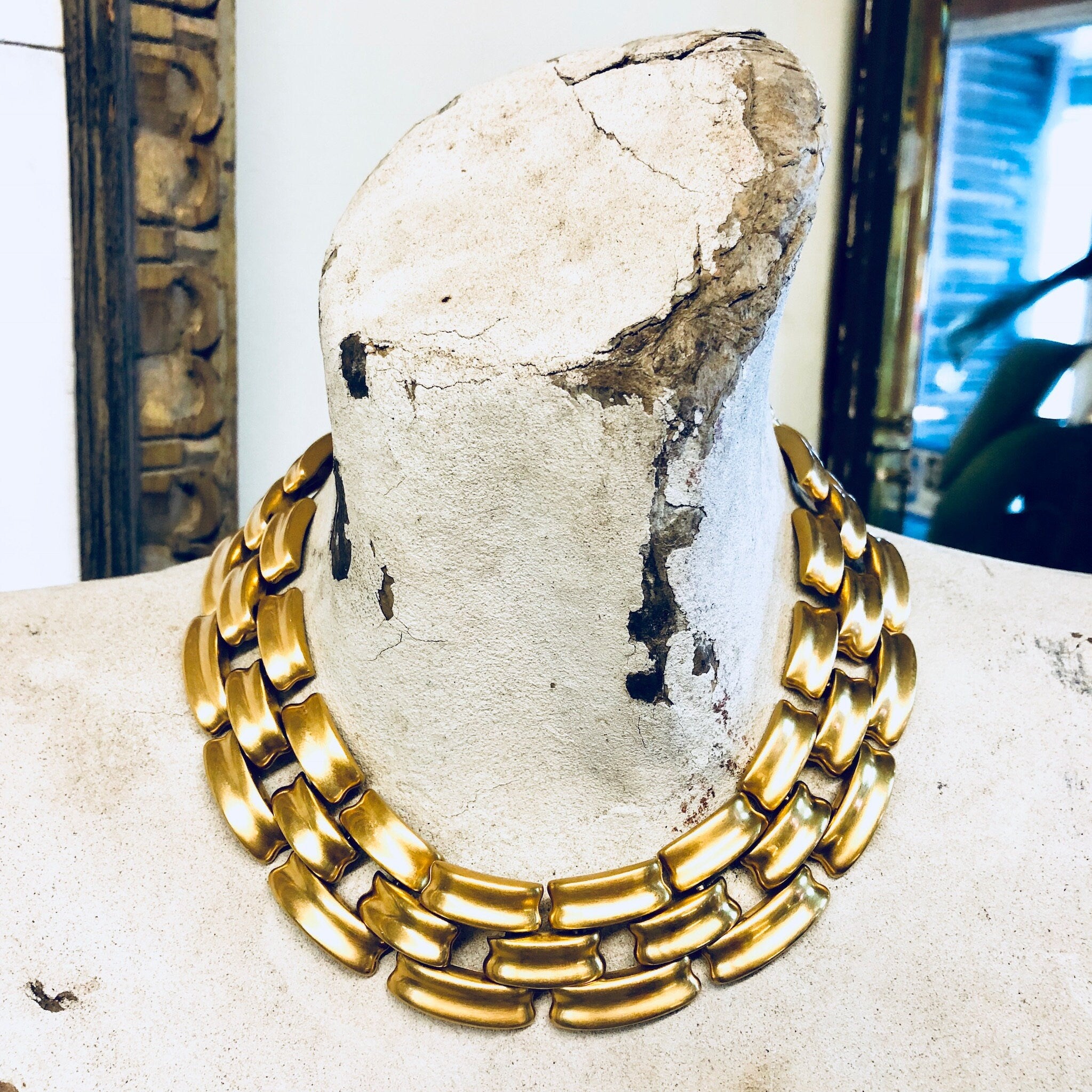 Vintage gold-toned Anne Klein chain link choker necklace with thick links and toggle clasp, displayed on weathered concrete surface.