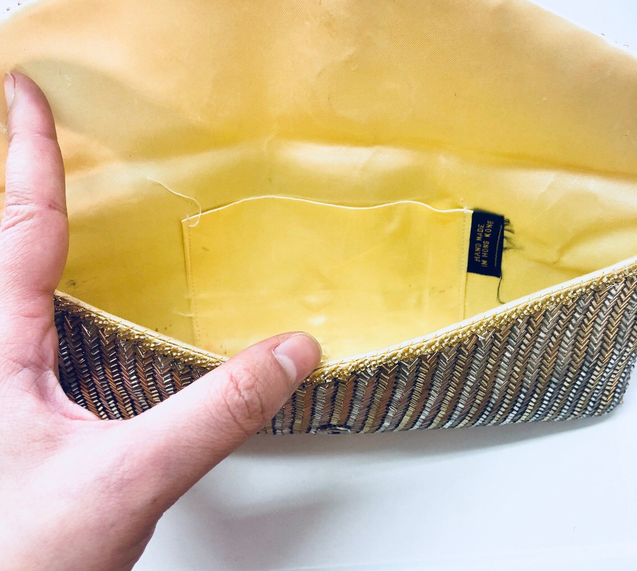 Vintage beaded gold and silver envelope clutch purse with yellow lining, held in hand, suitable for formalwear or weddings
