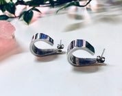 Vintage Zina sterling silver 925 modernist thick hoop earrings on white surface with pink quartz and greenery in soft focus background
