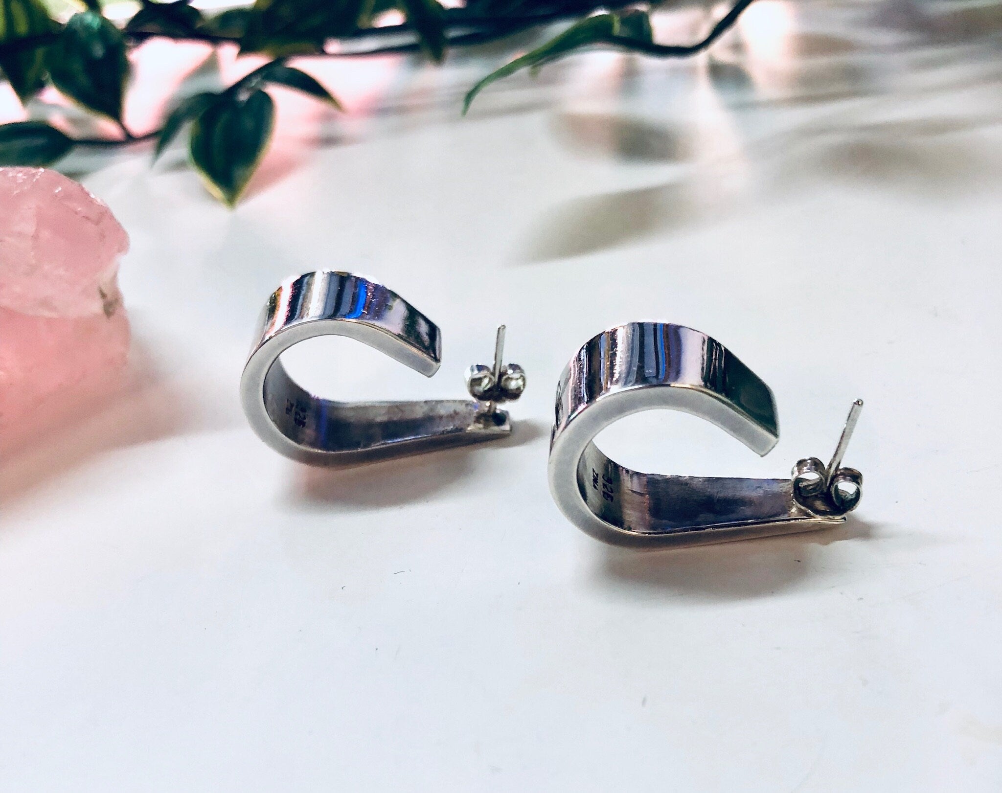 Vintage Zina sterling silver 925 modernist thick hoop earrings on white surface with pink quartz and greenery in soft focus background