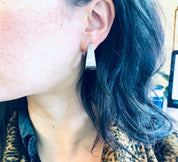 Close-up view of a woman wearing vintage modernist thick sterling silver Zina earrings, with long blue hair obscuring part of her face.